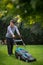 Down syndrome adult man mowing lawn outdoors in backyard, helping with housework concept.