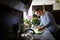 Down syndrome adult man standing indoors in kitchen at home, helping.