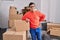 Down syndrome man smiling confident leaning on package at new home