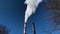 Down view of white smoke from the thermal power factory chimney on blue sky