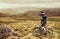 Downhill rider on a mountain bike in a mountain bike rides along the road in nature against the backdrop of the mountain