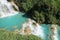 Downstream of a waterfall with turquoise pools and faint rainbow