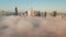 Downtown high rise buildings above dense fog. Descending footage gradually limiting visibility of town. Warsaw, Poland