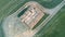 Downward view aerial video of flight above hay stack between two fields