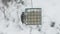 Downy woodpecker feeding on a suet from feeder, blizzard conditions