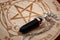 Dowsing pendulum with black gemstone next to hardwood divination chart on red velvet backgrounds concept for mystic magic spell,