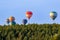 A dozen bright multicolored balloons in flight against a background of blue sky.