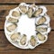 Dozen Chesapeake Bay raw oysters simply arranged on a paper plate and served on picnic table.