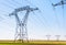 Dozens of electricity pylons in the countryside under a clear blue sky