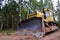 Dozer during clearing forest for construction new road . Yellow Bulldozer at forestry work Earth-moving equipment at road work,