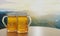 Draft or craft beer in clear glass with beer foam on top Put on set of wooden tables and chairs. Lounge seating on the wooden