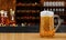 Draft or craft beer in tall clear glass. With cold steam, White beer foam placed on a wooden floor, behind the background is a