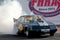 A drag race car speeding up in quarter mile race with nitro burning