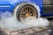 Drag racing car burning tire at starting line in race track