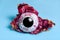 Dragon Fruit or Pitaya half peeled from the skin with black circle depicting eye pupil on blue background