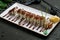 The dragon roll with eel on white plate on dark stone table