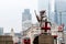 A dragon sculpture with the Coat of Arms of the City of London at the London Bridge. Blurred skyscrapers and red double decker