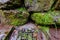 Drainage on a stone floor on a path with a mossy rock fence