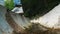 Drainage system in the forest. Water flowing through the channel. Two tourists stepping over the forest drainage in the