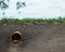 Drainpipe in the ground on a blurred background of the river