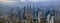 Dramatic aerial panorama photograph of Kuala Lumpur city skyline during hazy sunrise.