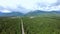 Dramatic aerial view of mountains, green forest landscape, road and town