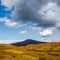 Dramatic autumn landscape with black mountain in gold sunshine. Beautiful mountain scenery with sunlit golden autumn plateau and