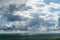 Dramatic beautiful sky with clouds and blue patches in between over a hilly green terrain