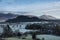 Dramatic beautiful Winter landscape image looking across countryside in Lake District with hard frost on the ground and crisp blue