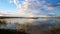 Dramatic blue evening tranquil sunset sky over dry grass field at pond lake shore. Rural countryside serene cloudscape