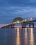 Dramatic blue hour stormy scene over a long steel tied arch bridge. Fire Island