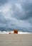 Dramatic cloudy minimalist beach view with a wooden dressing cabin. changing room