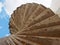 Dramatic curving concrete outdoor spiral staircase in stained brown colors against a blue cloudy sky