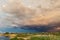 Dramatic dark cloudy thunder sky over dry grass field at pond shore. Rural countryside rainy ominous cloudscape over dry autumn