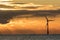 Dramatic dark sunrise sky with solitary offshore wind turbine silhouette