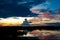 Dramatic evening sky over lake in Botswana with dark and orange clouds, bright blue sky and reflections in water at sunset.