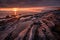 Dramatic, fiery sunset over the rocky shore with water puddles