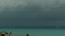 Dramatic gloomy sky with dark thunderstorm clouds over turquoise sea. Hurricane on ocean horizon. Vivid aerial timelapse