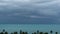 Dramatic gloomy sky with dark thunderstorm clouds over turquoise sea. Hurricane on ocean horizon. Vivid aerial timelapse