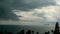 Dramatic gloomy sky with dark thunderstorm clouds over turquoise sea. Hurricane on ocean horizon. Vivid aerial timelapse