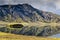 Dramatic iceland landscape with a green hill and black lava and and blue mirror mountain lake. Iceland