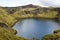 Dramatic iceland landscape with a green hill and black lava and and blue mirror mountain lake. Iceland