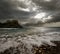 Dramatic landscape - dark stormy sky and sunlight, sea waves, co