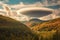 dramatic lenticular cloudscape above a forested mountain valley