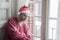 Dramatic lifestyle portrait of sad and depressed man in Santa Claus hat feeling lonely home alone by Christmas holiday thoughtful