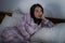 Dramatic lifestyle portrait of young attractive sad and depressed Asian Korean woman on bed awake at night feeling stressed and