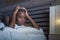 Dramatic lifestyle portrait of young sad and depressed black african American woman on bed sleepless suffering headache insomnia s