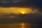 Dramatic light mood with orange illuminated clouds and the sun as a fiery ball during a sunrise over the Baltic Sea