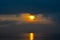 Dramatic light mood with orange illuminated clouds and the sun as a fiery ball during a sunrise over the Baltic Sea