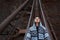 Dramatic outdoor portrait of young, thoughtful hooded girl, lying on old rusty bridge. Perspective concept.